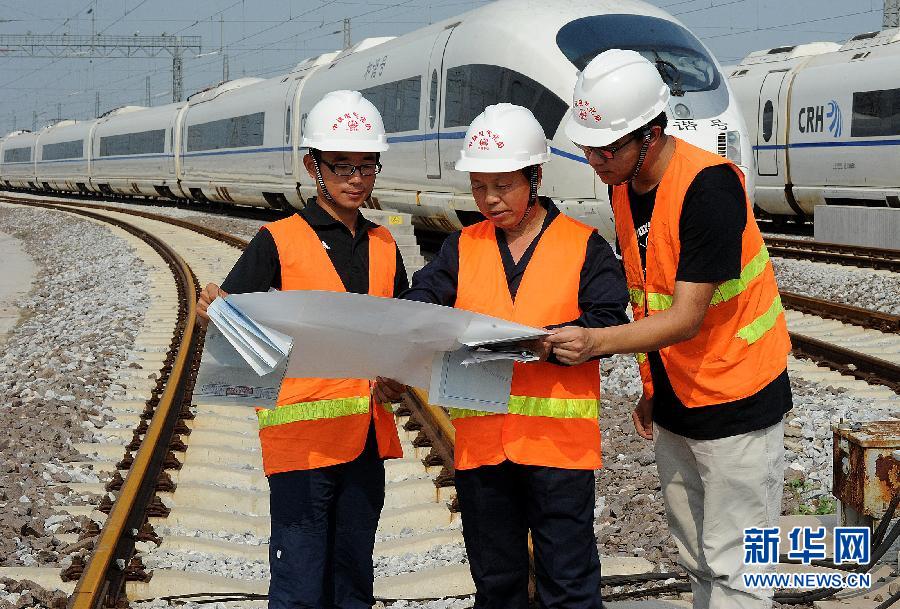 8月16日,巨晓林(中)在北京动车段电气化铁路接触网前给徒弟们讲实际