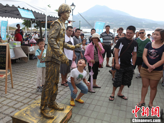 图为10月6日,一位艺人在淡水河边展示类似于人体雕塑的艺术,引来顽皮